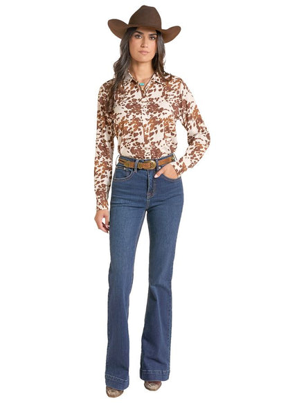woman wearing a cowhide print shirt from Panhandle Slim and blue jeans and a brown cowboy hat on a white background