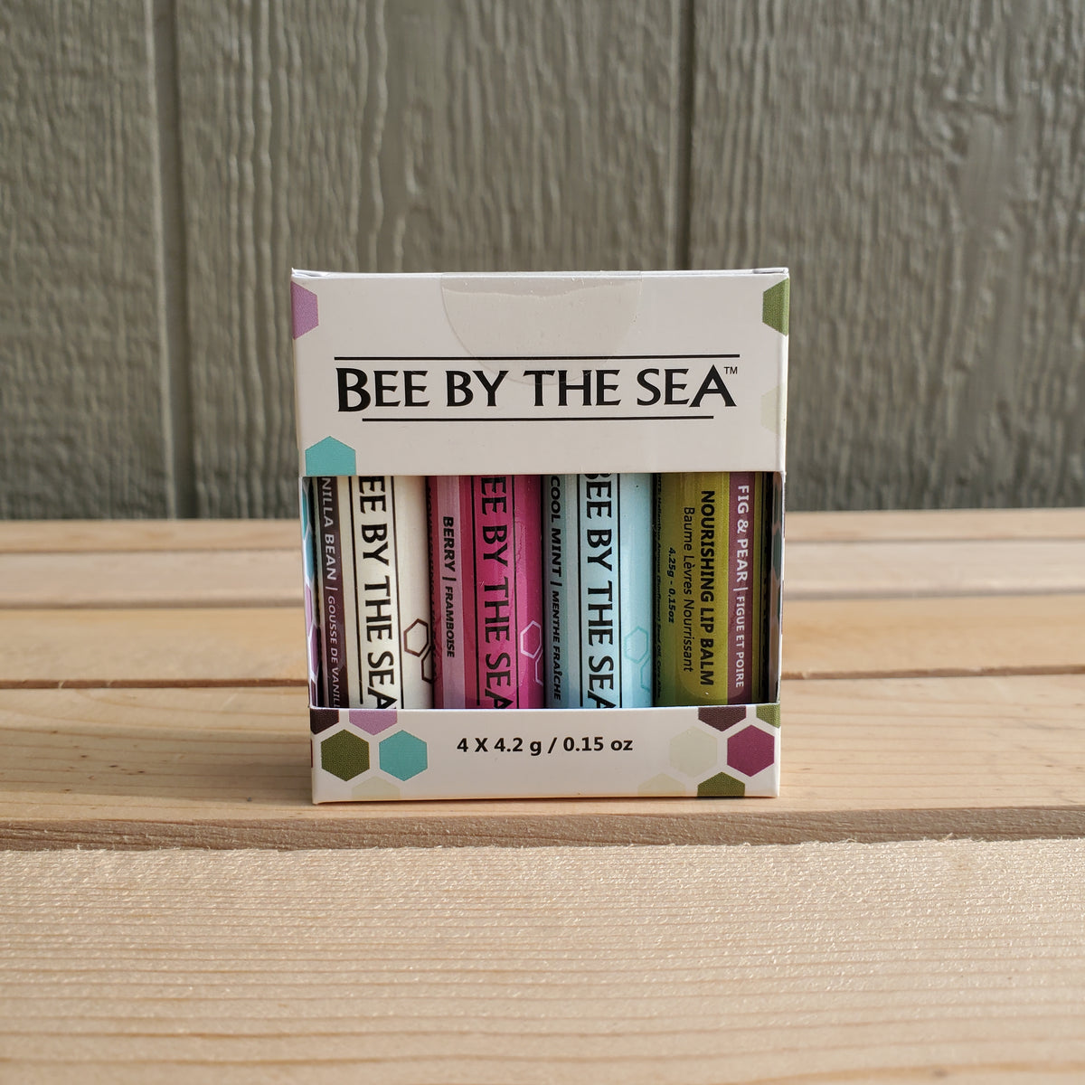 a four pack of lip balm by bee by the sea on a wooden background