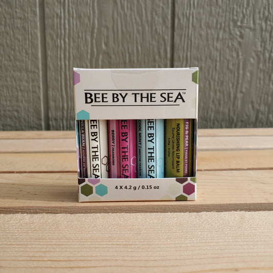 a four pack of lip balm by bee by the sea on a wooden background