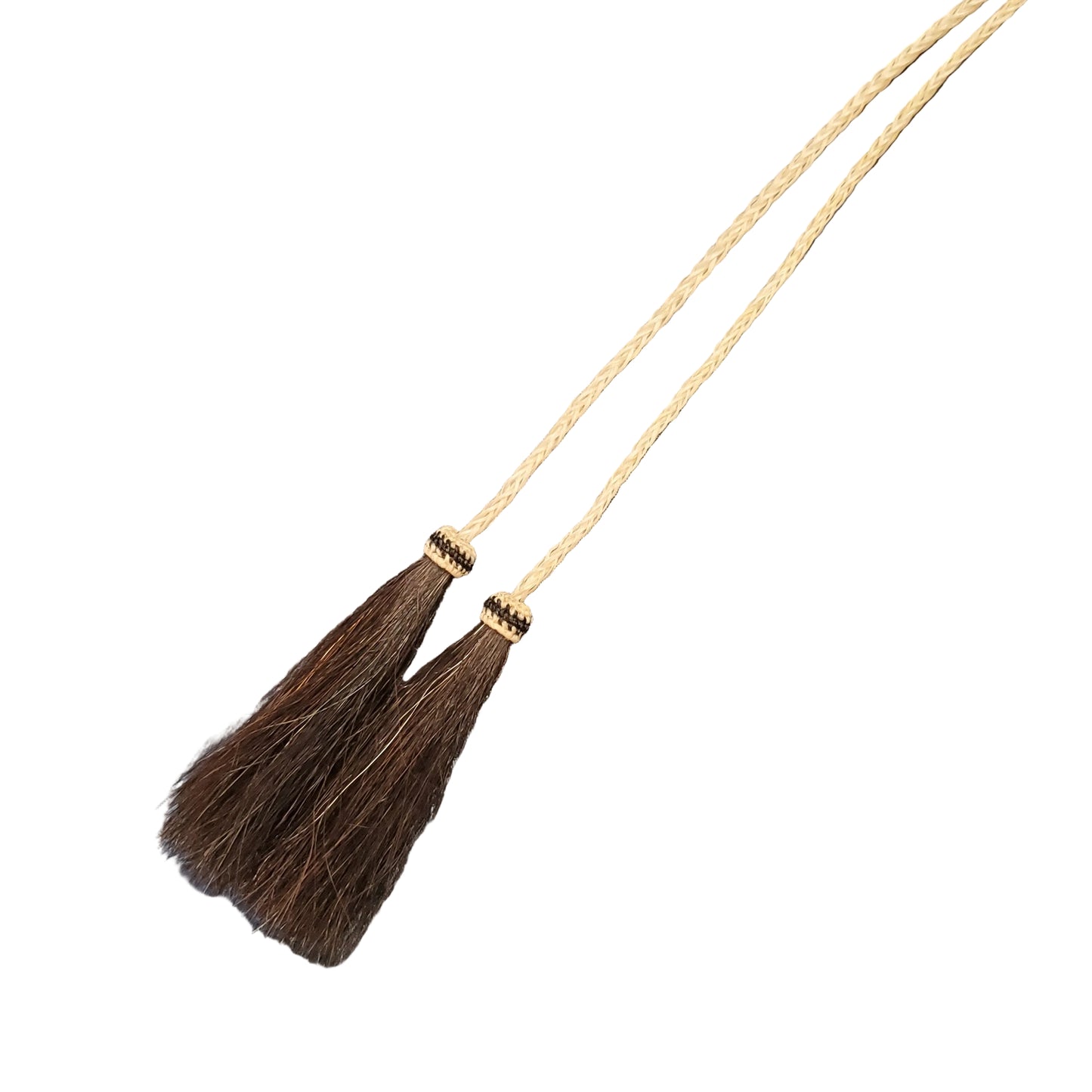 A close-up of a braided hair tassel necklace. The necklace features a thick cream-colored braided cord with two tassel ends, and finished with dark brown braided hair.