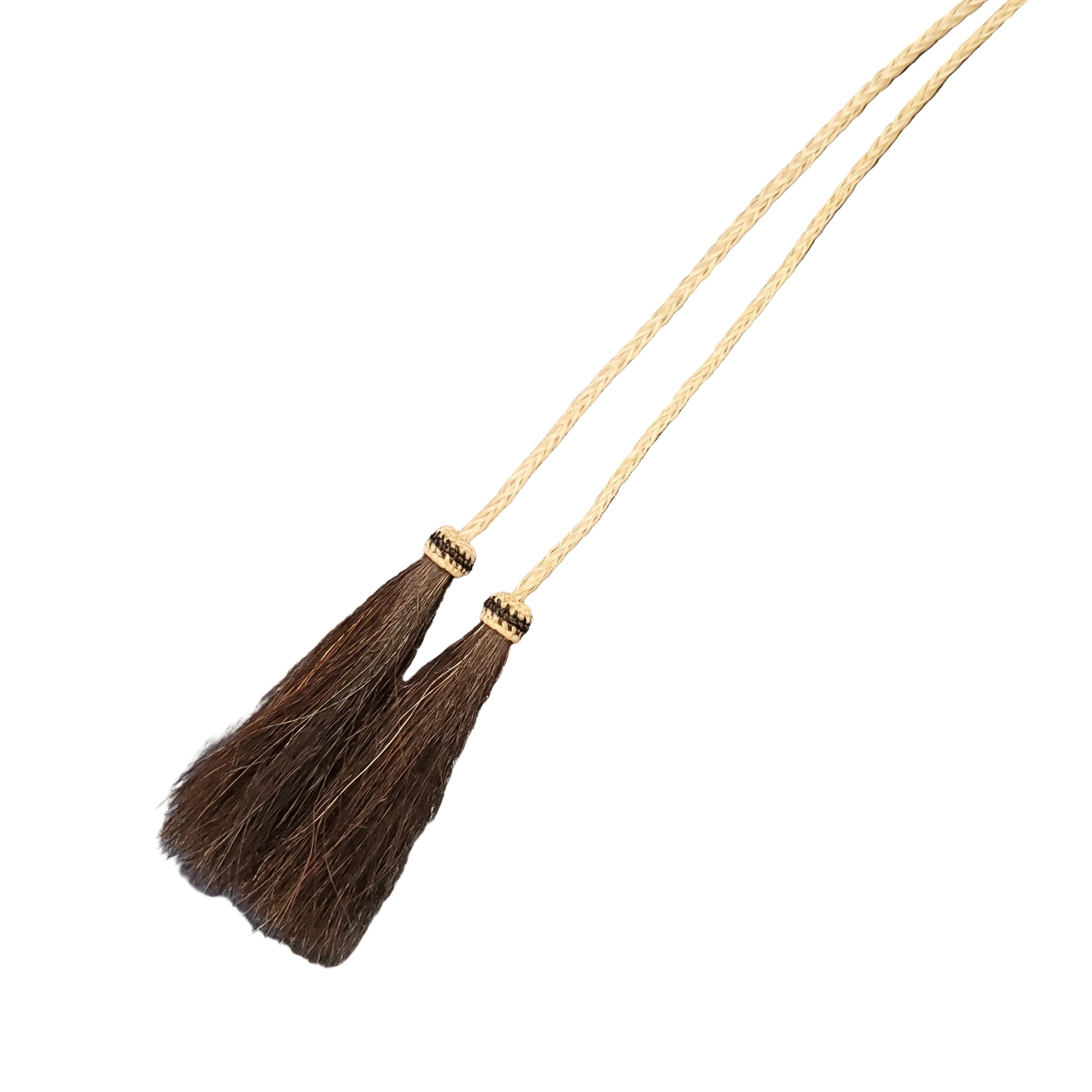 A close-up of a braided hair tassel necklace. The necklace features a thick cream-colored braided cord with two tassel ends, and finished with dark brown braided hair.