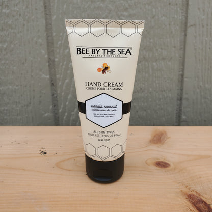 Hand cream tube labeled 'Bee by the Sea' on a wooden surface.