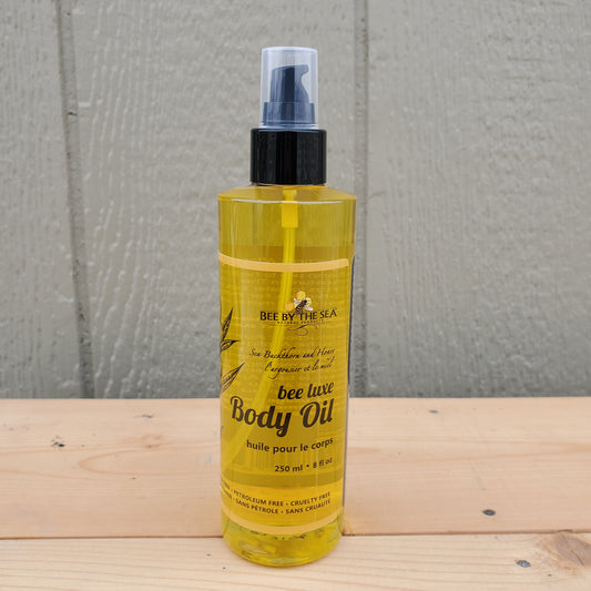 Bee by the sea body oil spray bottle on a wooden surface with a green background