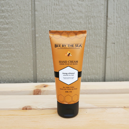 Hand cream tube labeled 'Bee by the Sea' on a wooden surface.