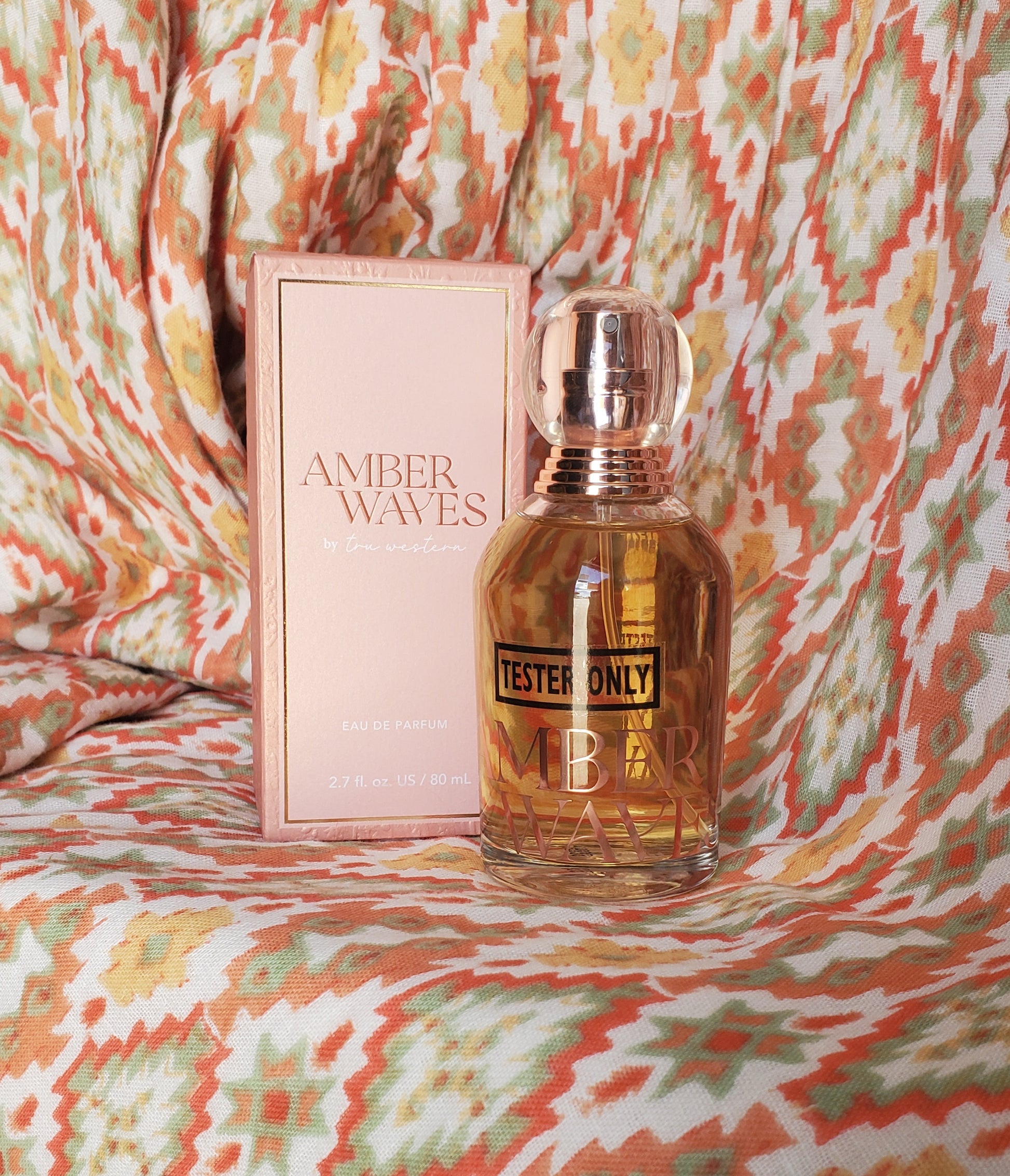 Perfume bottle and packaging on a patterned fabric background