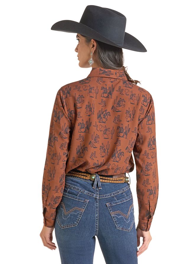 woman wearing a brown Panhandle Slim shirt with print on it, blue jeans and a black cowboy hat on a white background