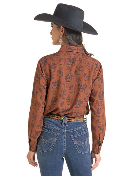 woman wearing a brown Panhandle Slim shirt with print on it, blue jeans and a black cowboy hat on a white background