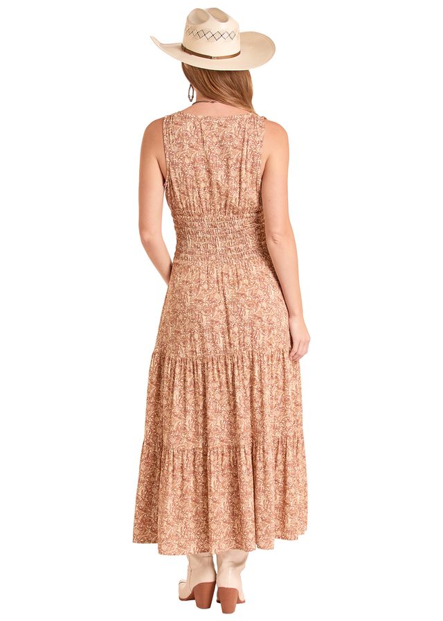 A woman shown from the back wearing a sleeveless, tiered maxi dress with a warm beige and rust-orange floral pattern, paired with a cream cowboy hat and light-colored heels, against a plain white background.