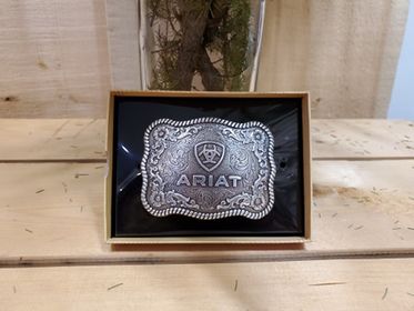 Belt buckle with rope edge and Ariat logo on a wooden background