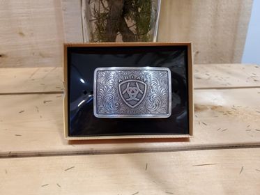 Rectangle belt buckle with ariat logo with wooden background