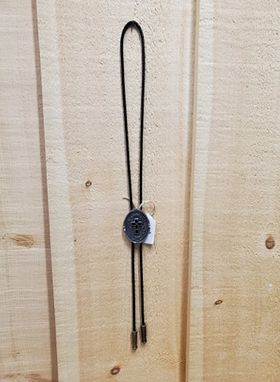 an antique grey cross pendant bolo tie on a wooden background