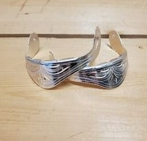 a pair of silver heel caps that are decorations to put on cowboy boots on a wooden background