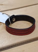 A red leather bracelet with a stamped pattern, displayed on a wooden surface.