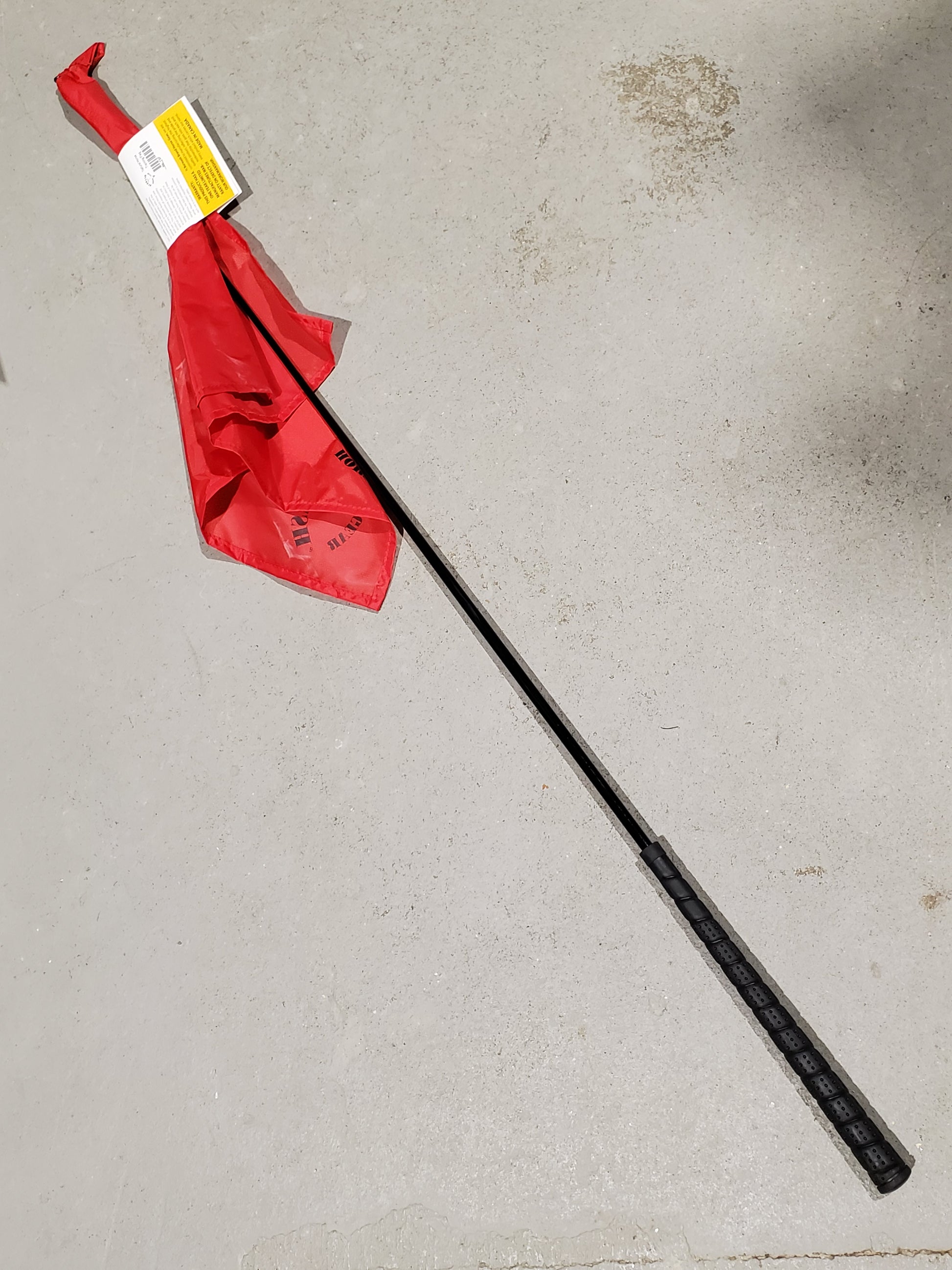 a red flag on the end of a black stick on a cement background