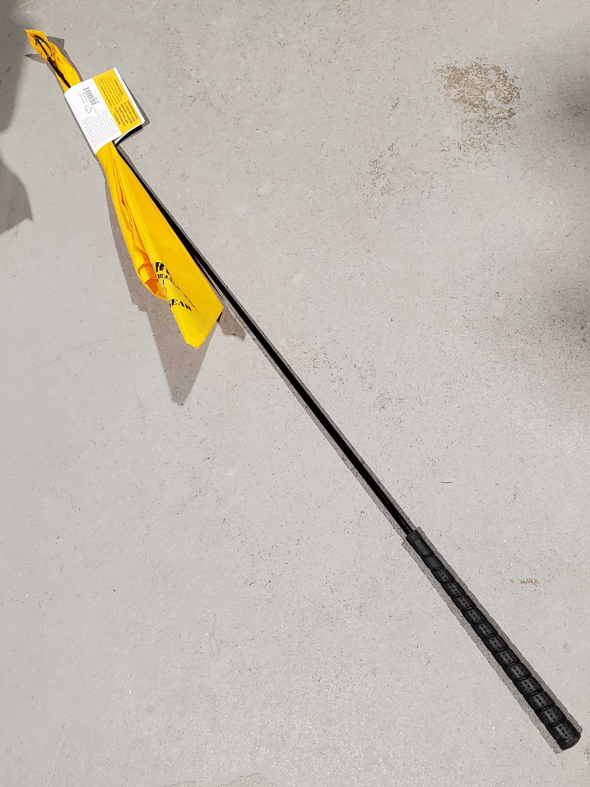 a yellow flag on the end of a black stick on a cement background