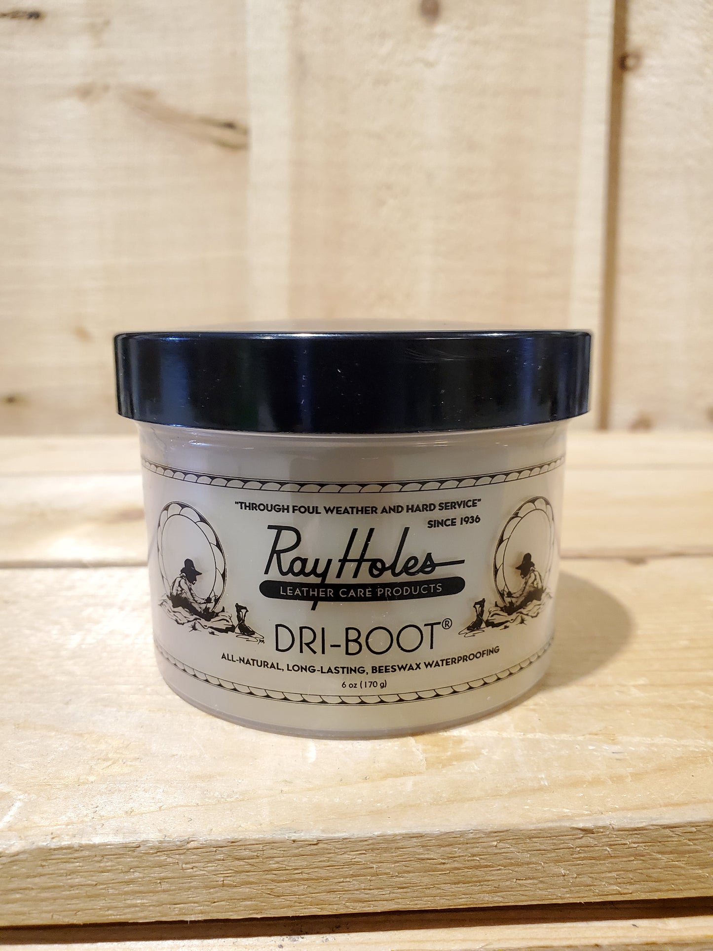 A container of Ray Hole's Dri-Boot waterproofing cream for leather gear, with the product label visible. on a wooden background