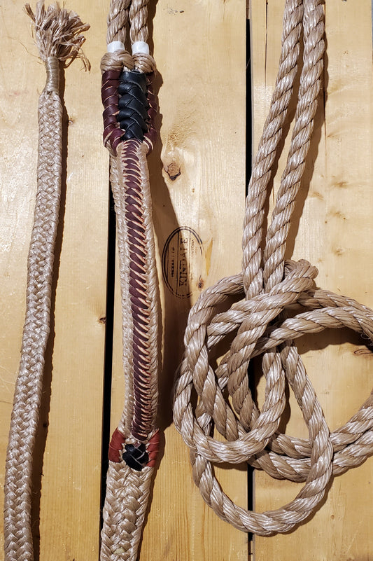 A coiled bull rope with a beige handle and a lace-up detail, placed on a wooden surface.