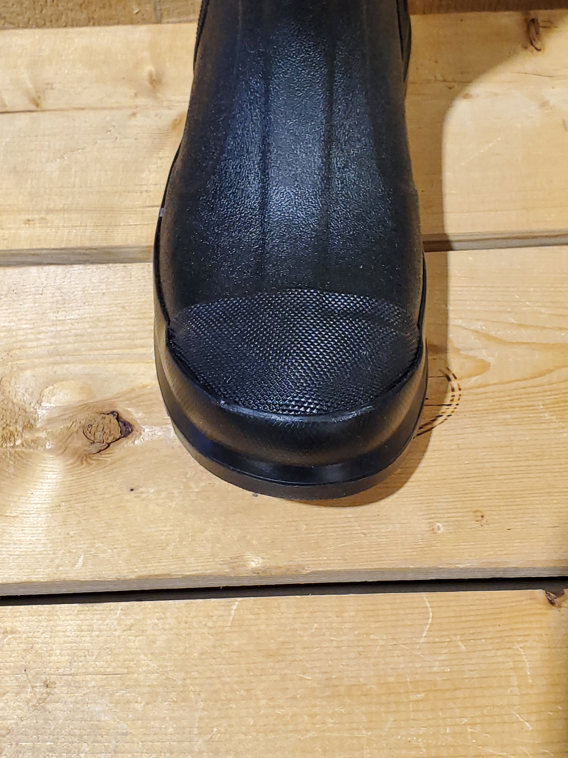 a close up of the toe of a black rubber boot