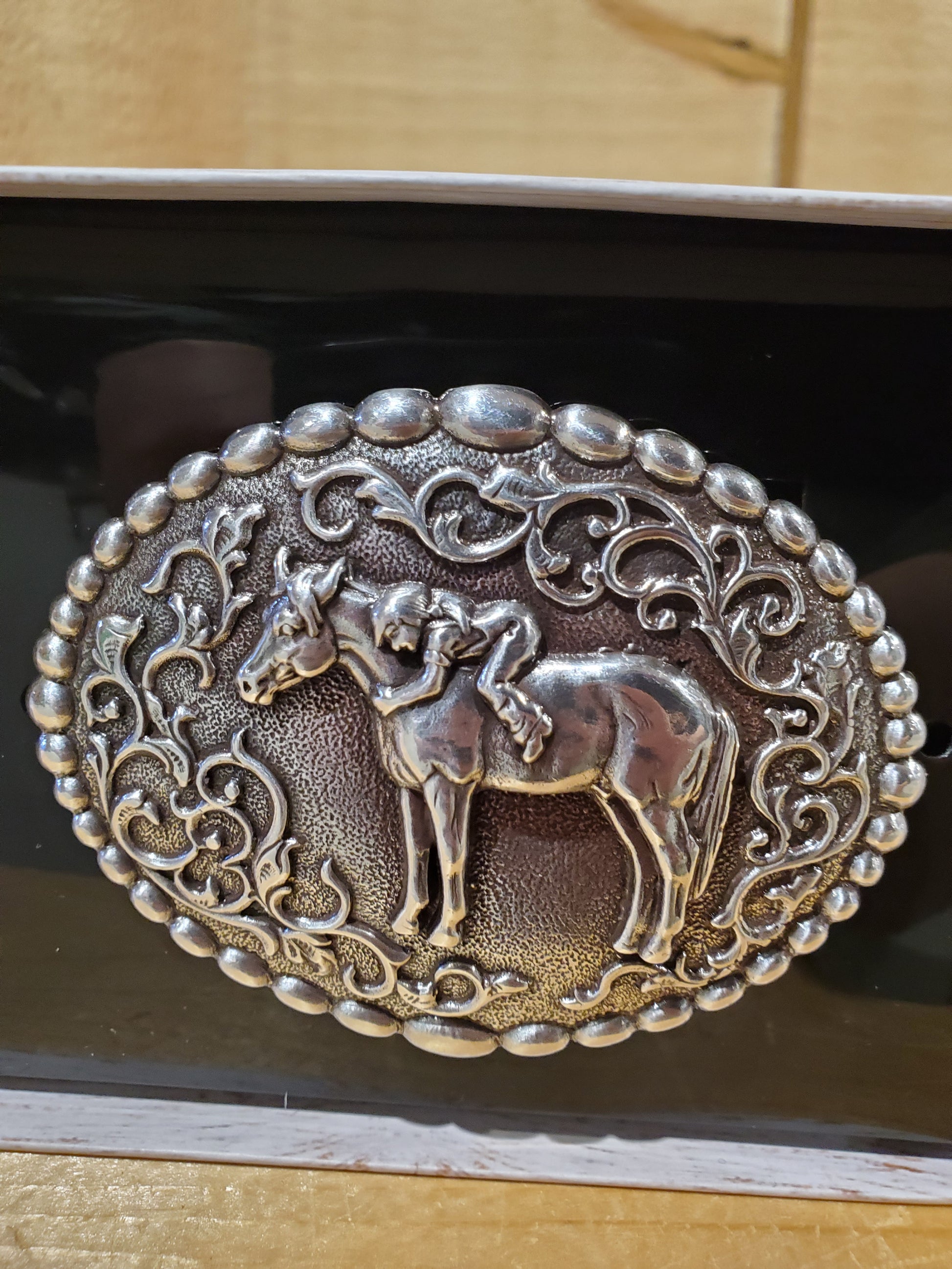 horse and girl belt buckle on a wooden background