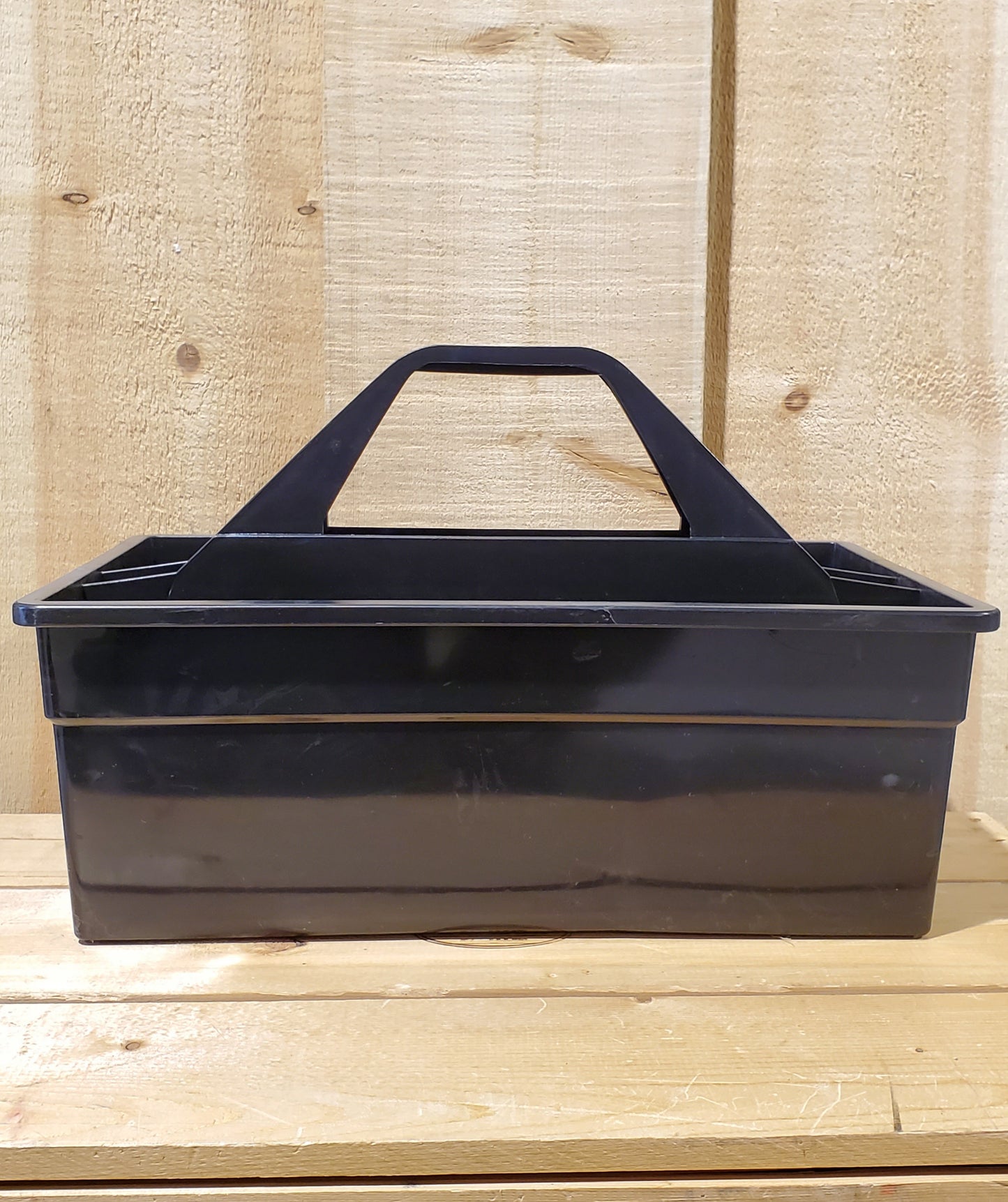 A black plastic utility tote with a handle, designed to be carried by hand and to fit onto a fence board.