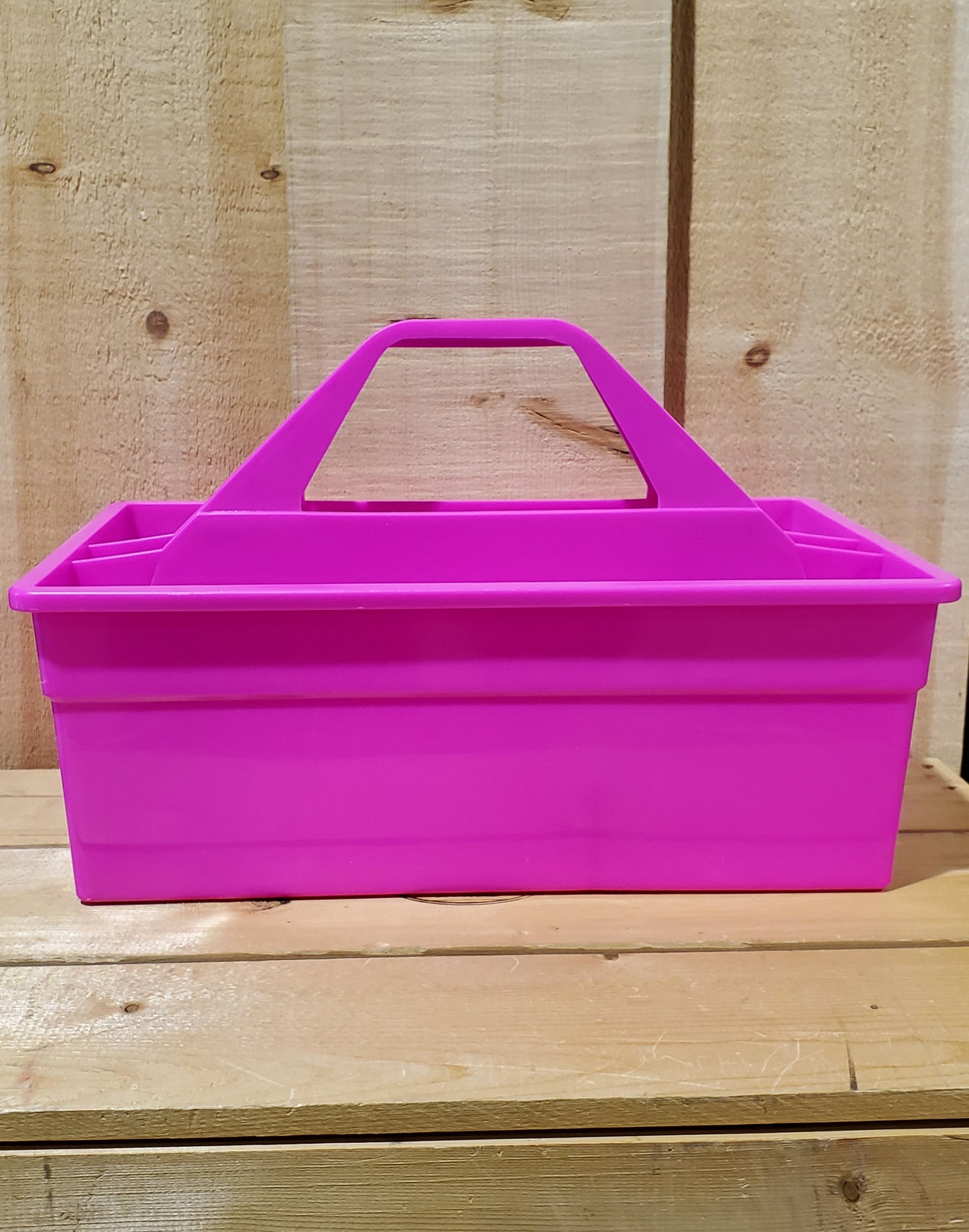 A pink plastic utility tote with a handle, designed to be carried by hand and to fit onto a fence board.