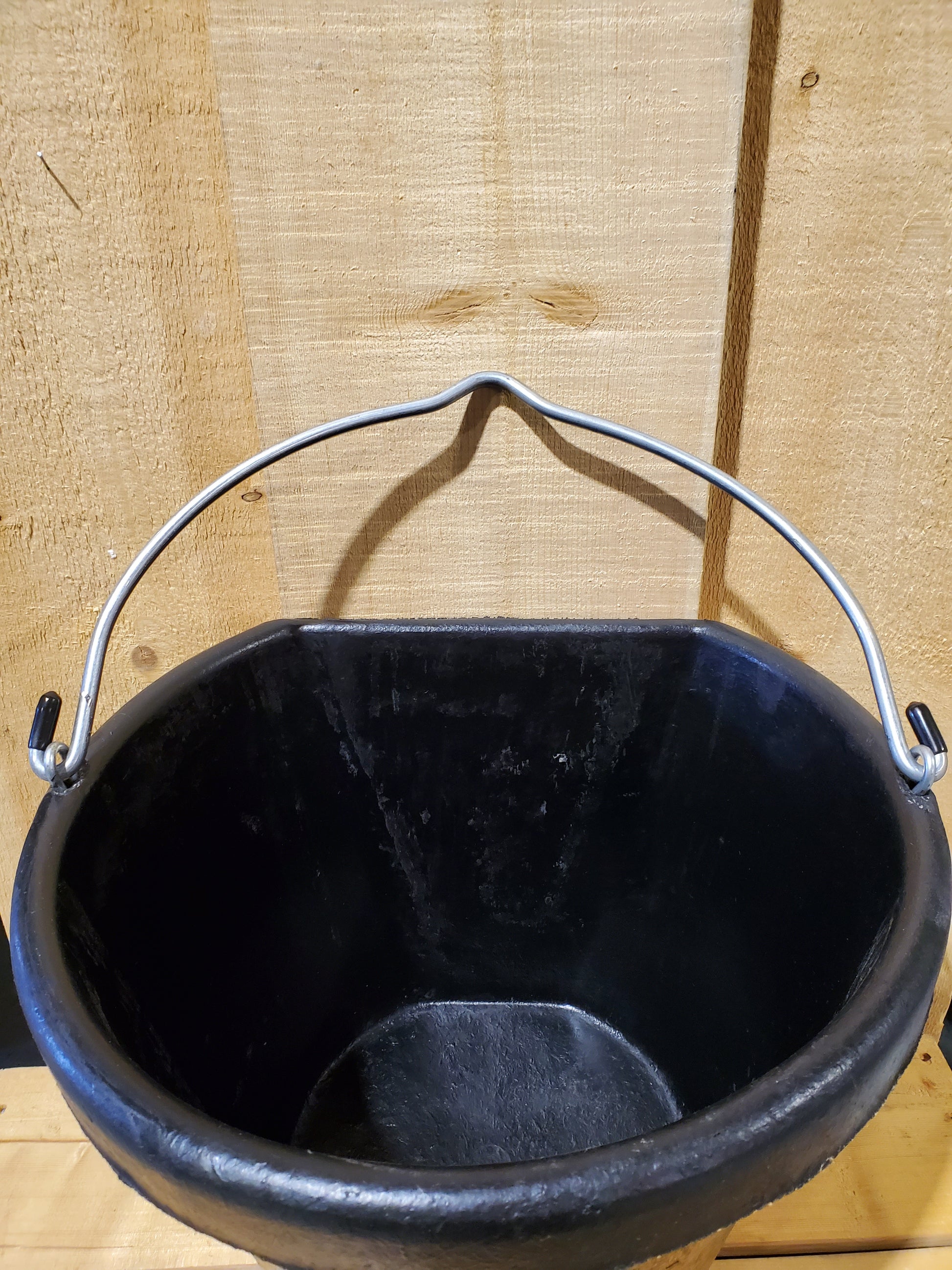 top view of a black rubber 18 qt bucket with handle on a wooden background