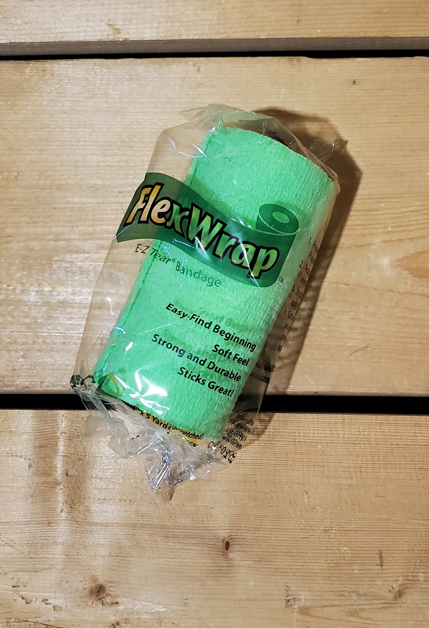 A rolled-up green FlexWrap E-Z Tear bandage, secured with a label that has the product name and details.