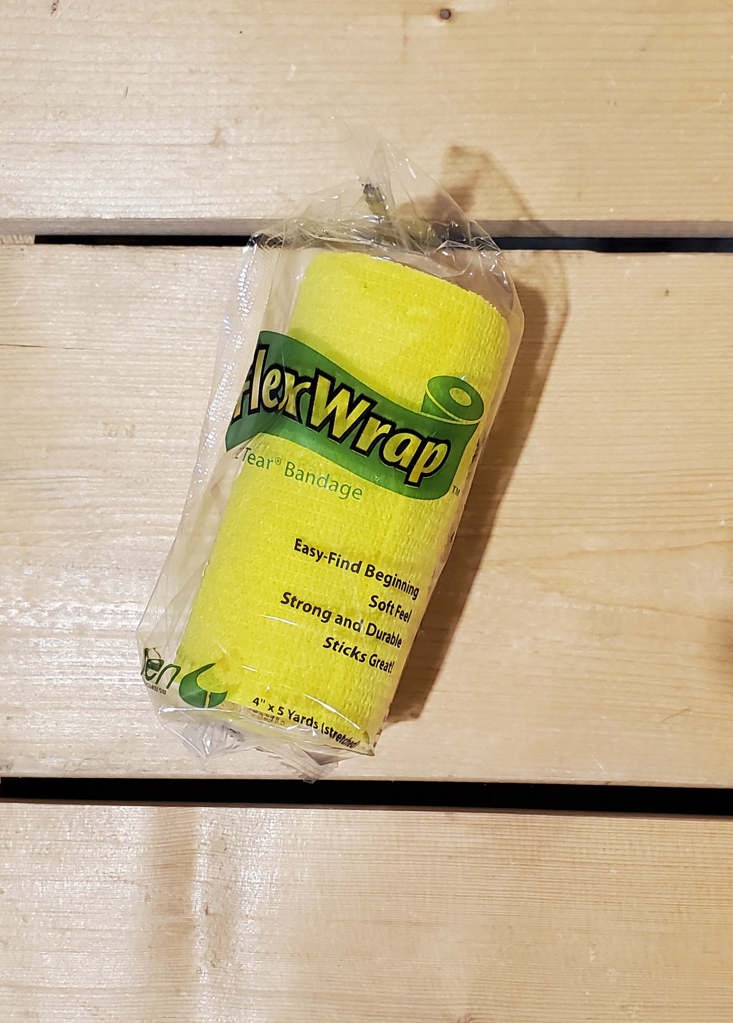 A rolled-up yellow FlexWrap E-Z Tear bandage, secured with a label that has the product name and details.