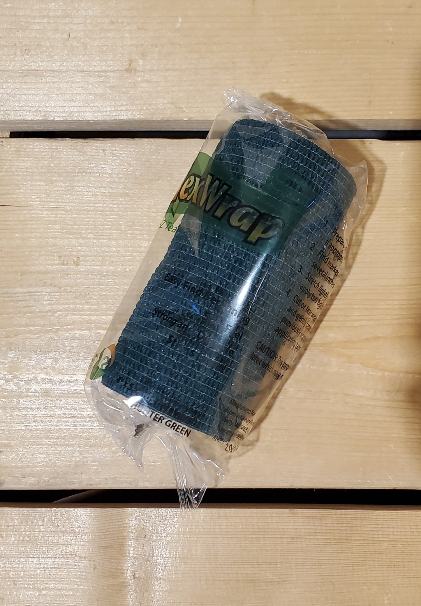 A rolled-up black FlexWrap E-Z Tear bandage, secured with a label that has the product name and details.