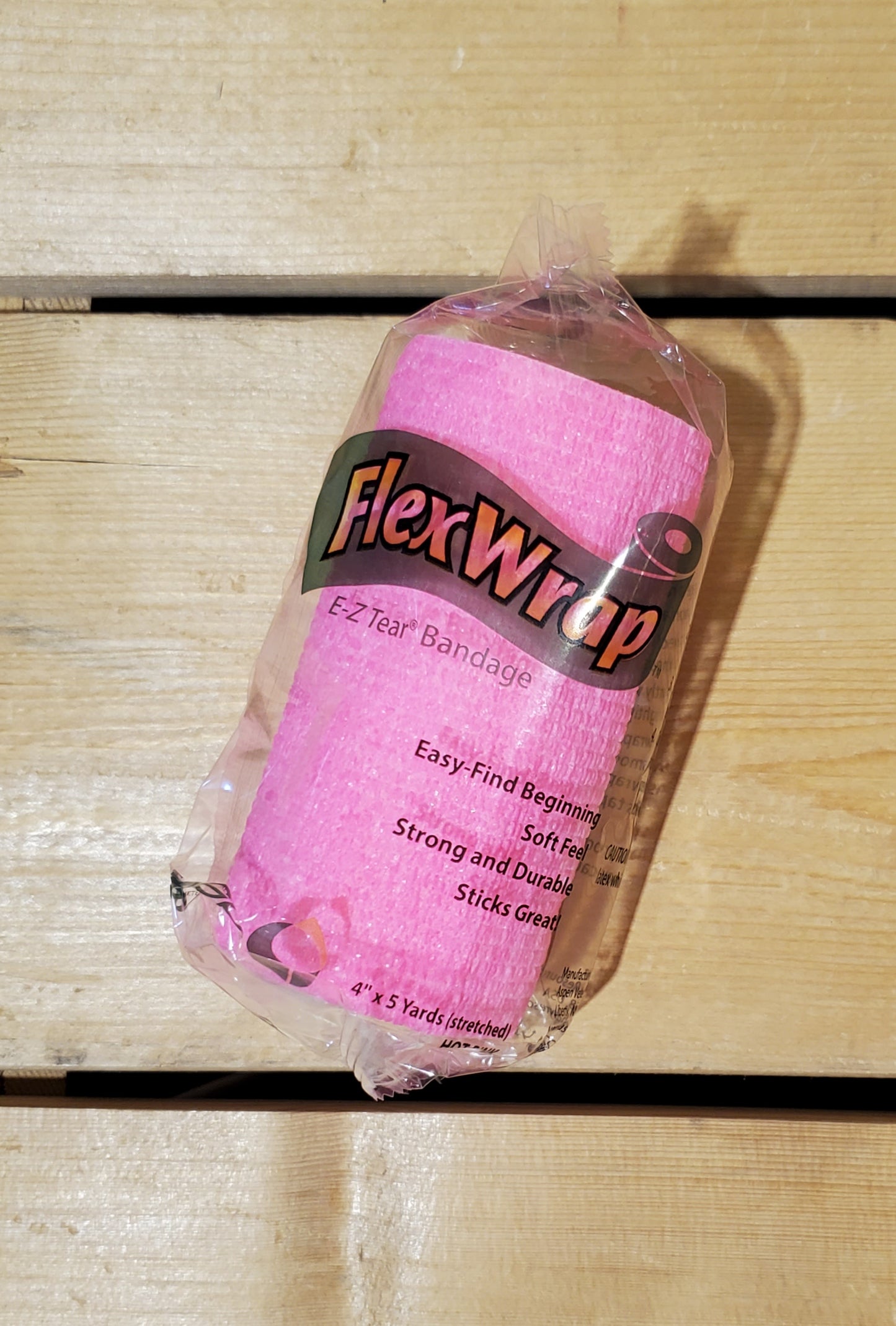 A rolled-up pink FlexWrap E-Z Tear bandage, secured with a label that has the product name and details.