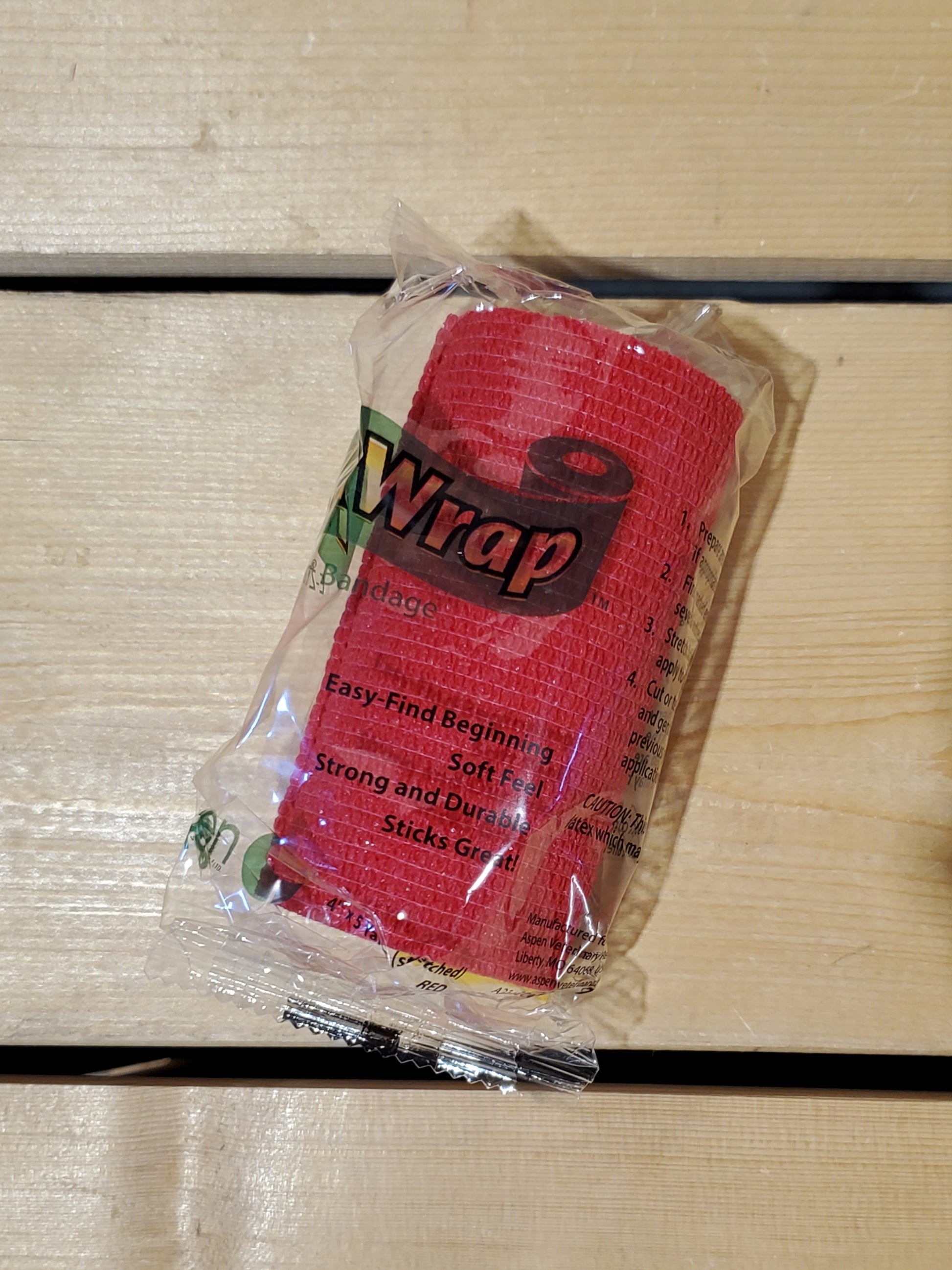 A rolled-up red FlexWrap E-Z Tear bandage, secured with a label that has the product name and details.
