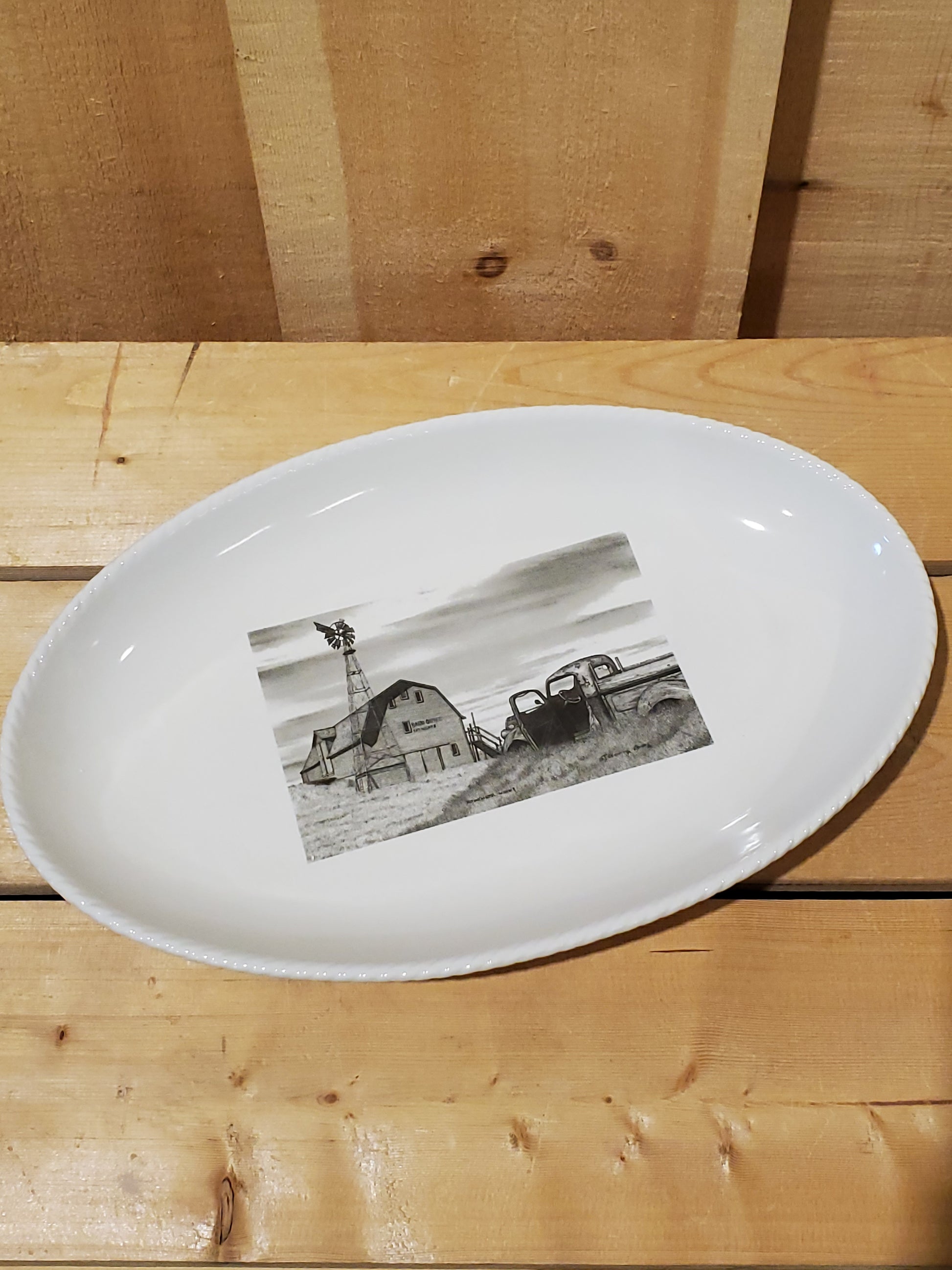 A white serving platter with a printed illustration featuring an old truck and barn