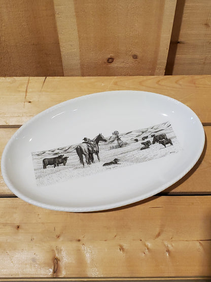A white serving platter with a printed illustration featuring a man and his horse looking at cows in a pasture