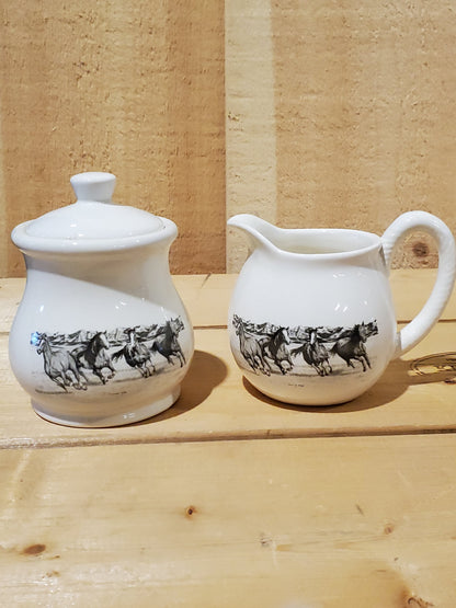 a white ceramic cream and sugar set with a black and white picture of running horses