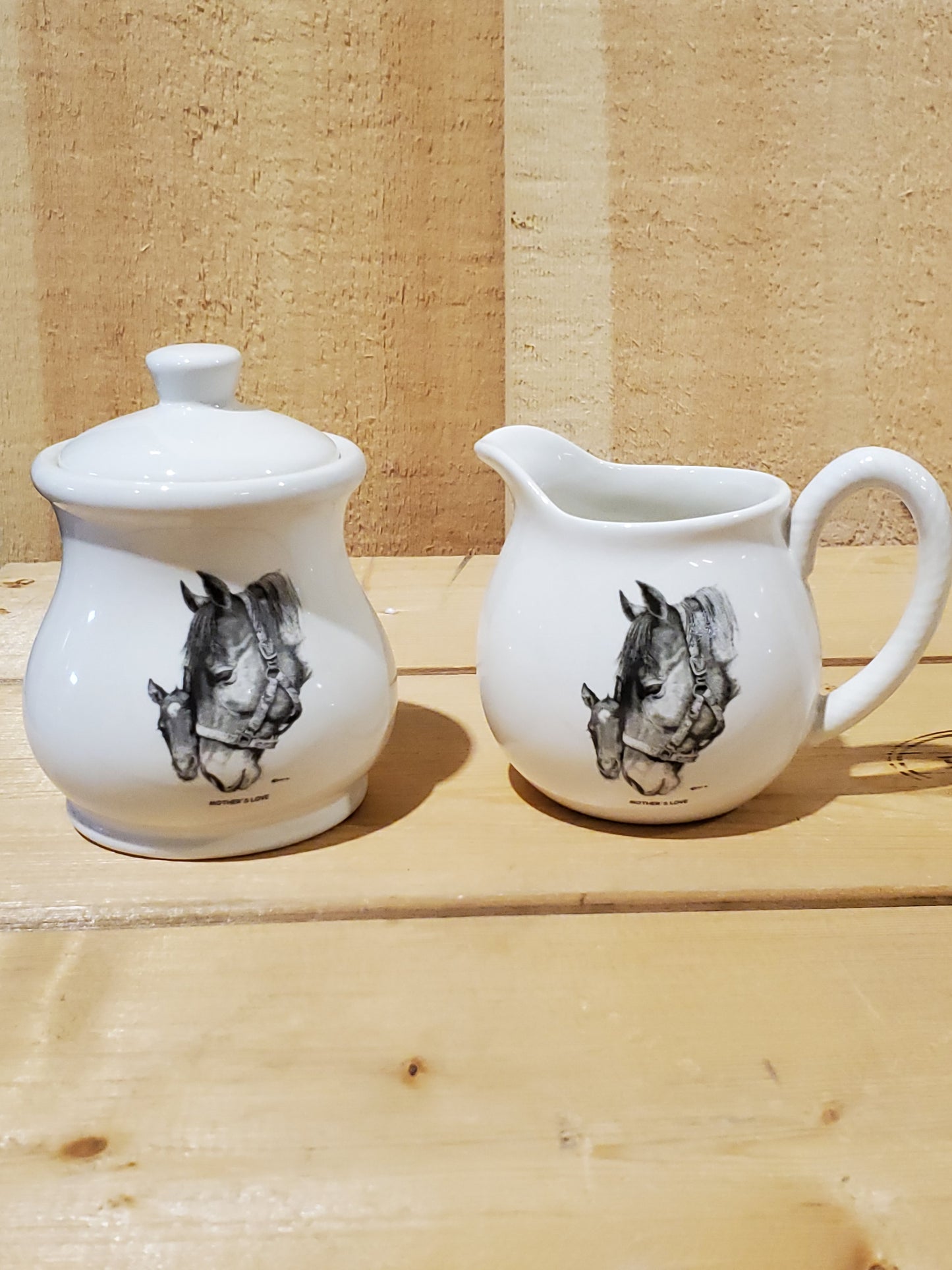 a white ceramic cream and sugar set with a black and white picture of a mare and foal on it