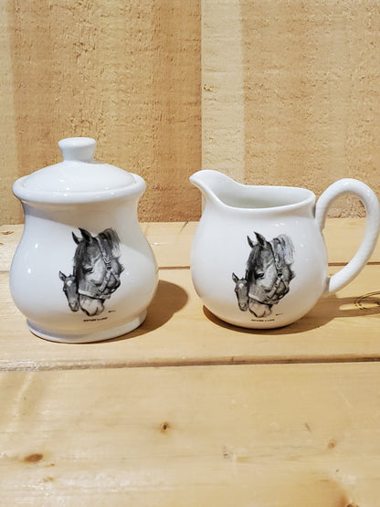 a white ceramic cream and sugar set with a black and white picture of a mare and foal on it