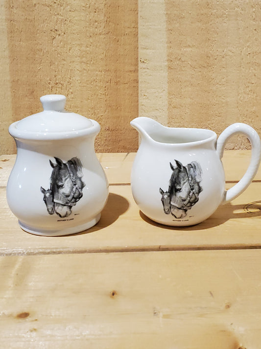 a white ceramic cream and sugar set with a black and white picture of a mare and foal on it