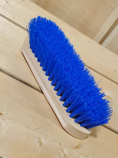 a blue medium bristle dandy brush on a wooden background