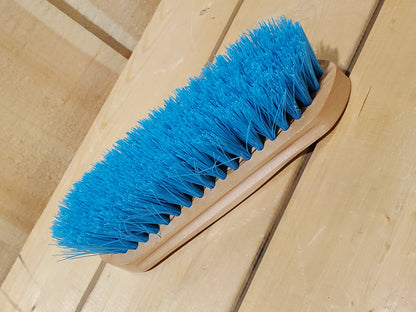 a teal medium bristle dandy brush on a wooden background