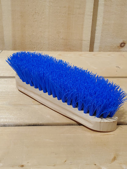 a blue hard bristled wooden handle dandy brush for horses on a wooden background