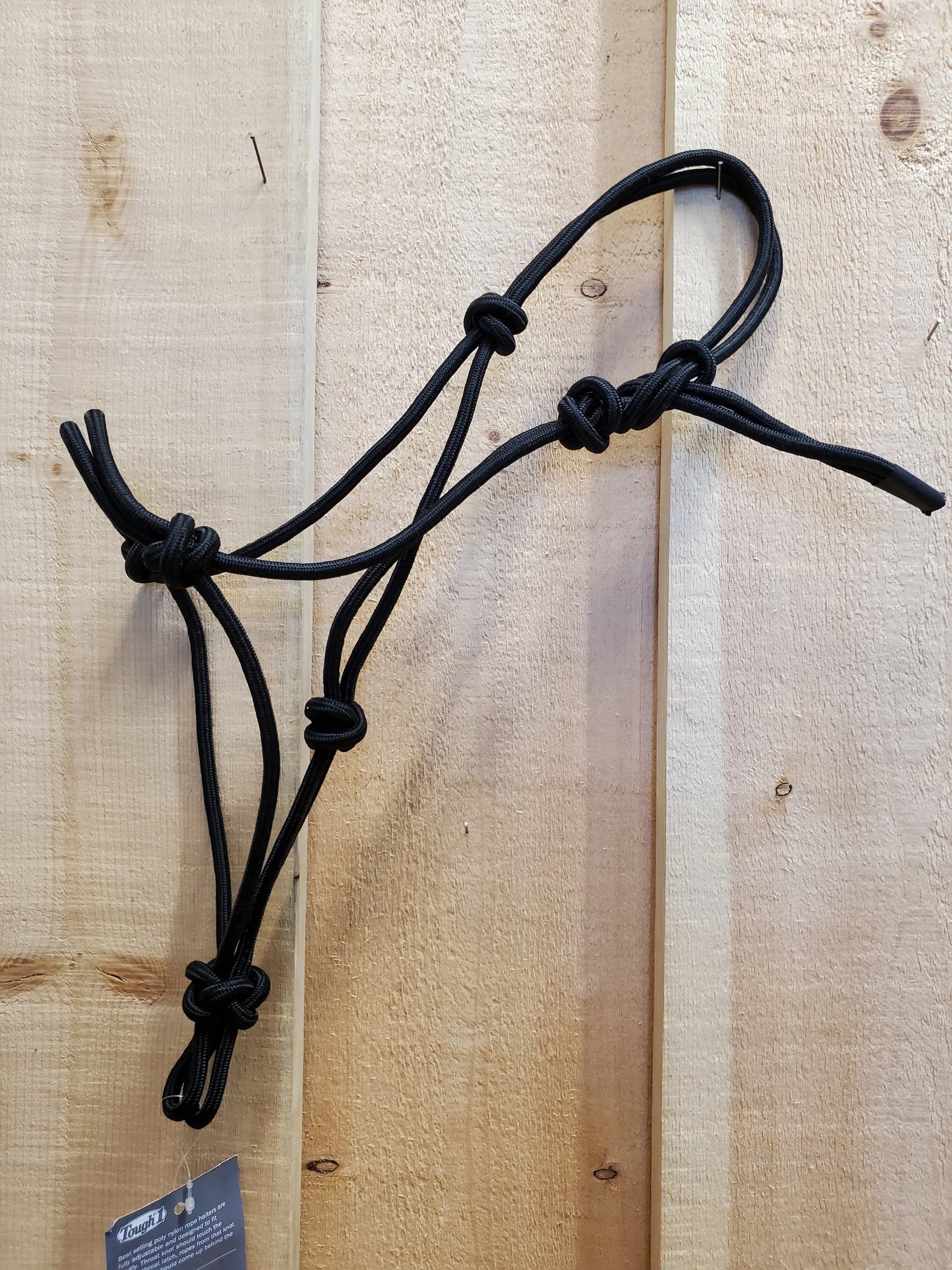 A black poly-nylon rope halter hanging against a wooden 