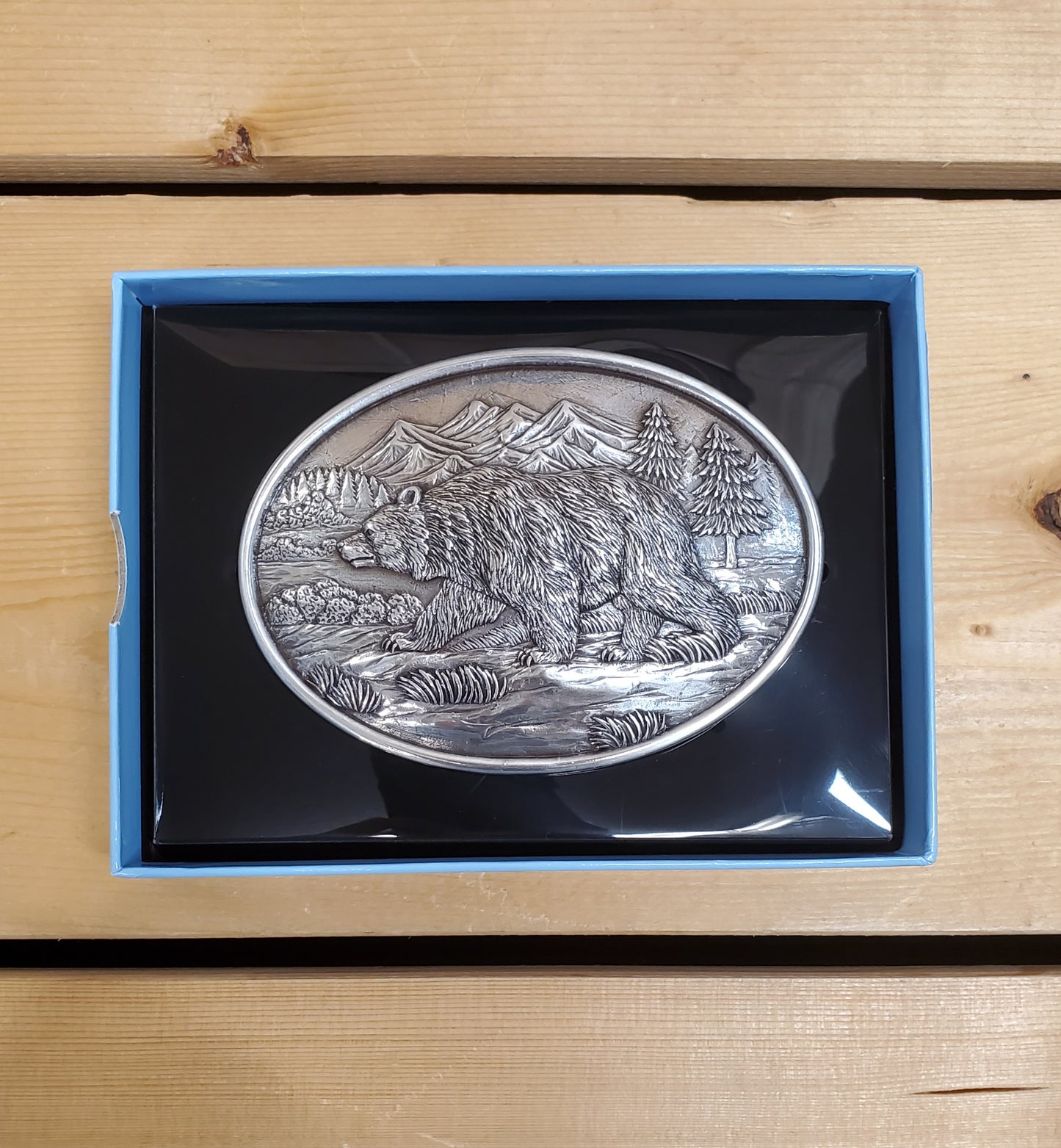 Belt buckle with grizzly bear decoration on a wooden background