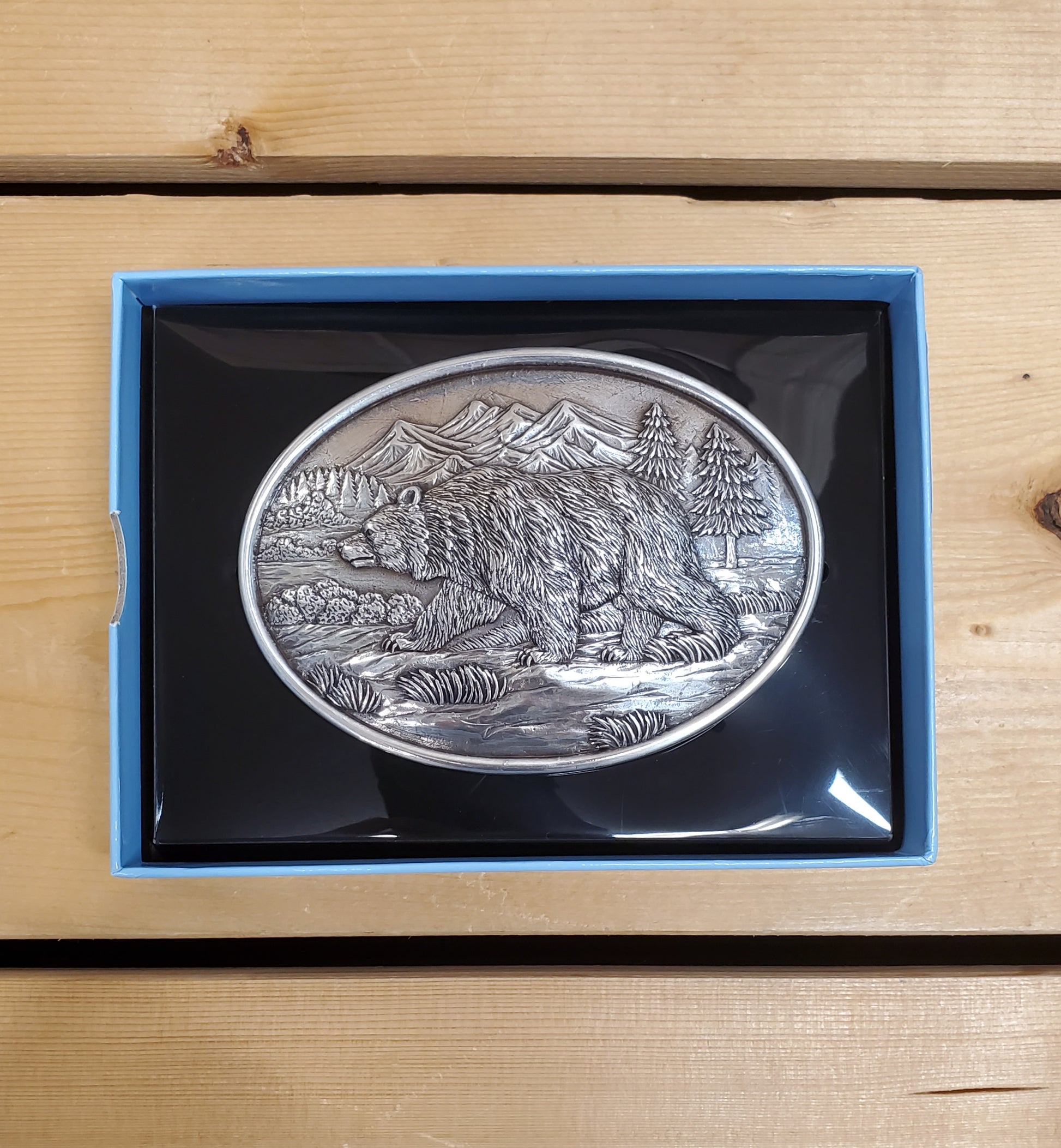 Belt buckle with grizzly bear decoration on a wooden background