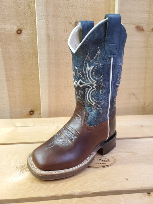 A kid's boot with a square toe, featuring white stitching on the shaft and a combination of navy blue and brown colors. 