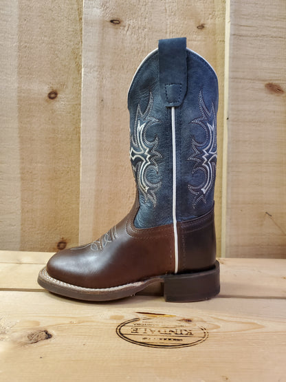 A kid's boot with a square toe, featuring white stitching on the shaft and a combination of navy blue and brown colors. 