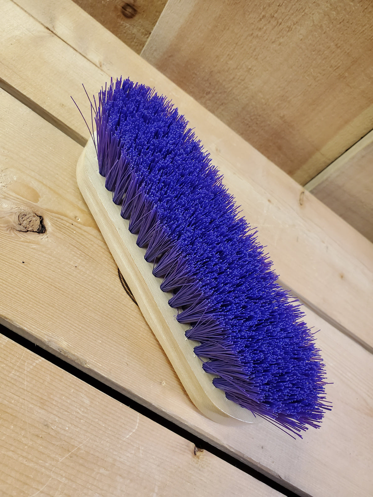 a blue medium bristle dandy brush on a wooden background