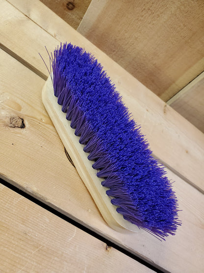 a blue medium bristle dandy brush on a wooden background
