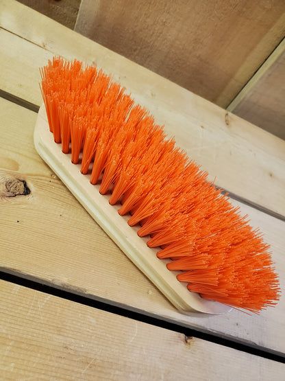an orange medium bristle dandy brush on a wooden background