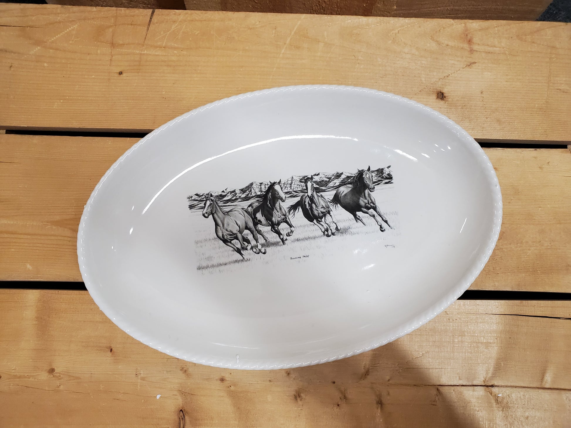 A white serving platter with a printed illustration featuring running horses