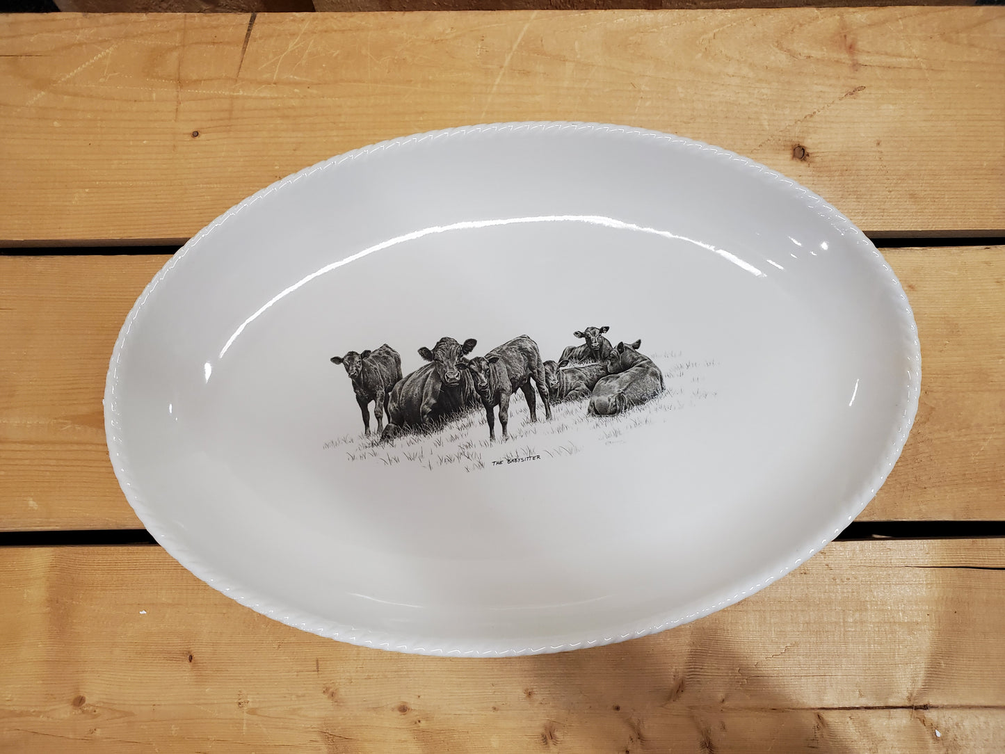 A white serving platter with a printed illustration featuring resting cows